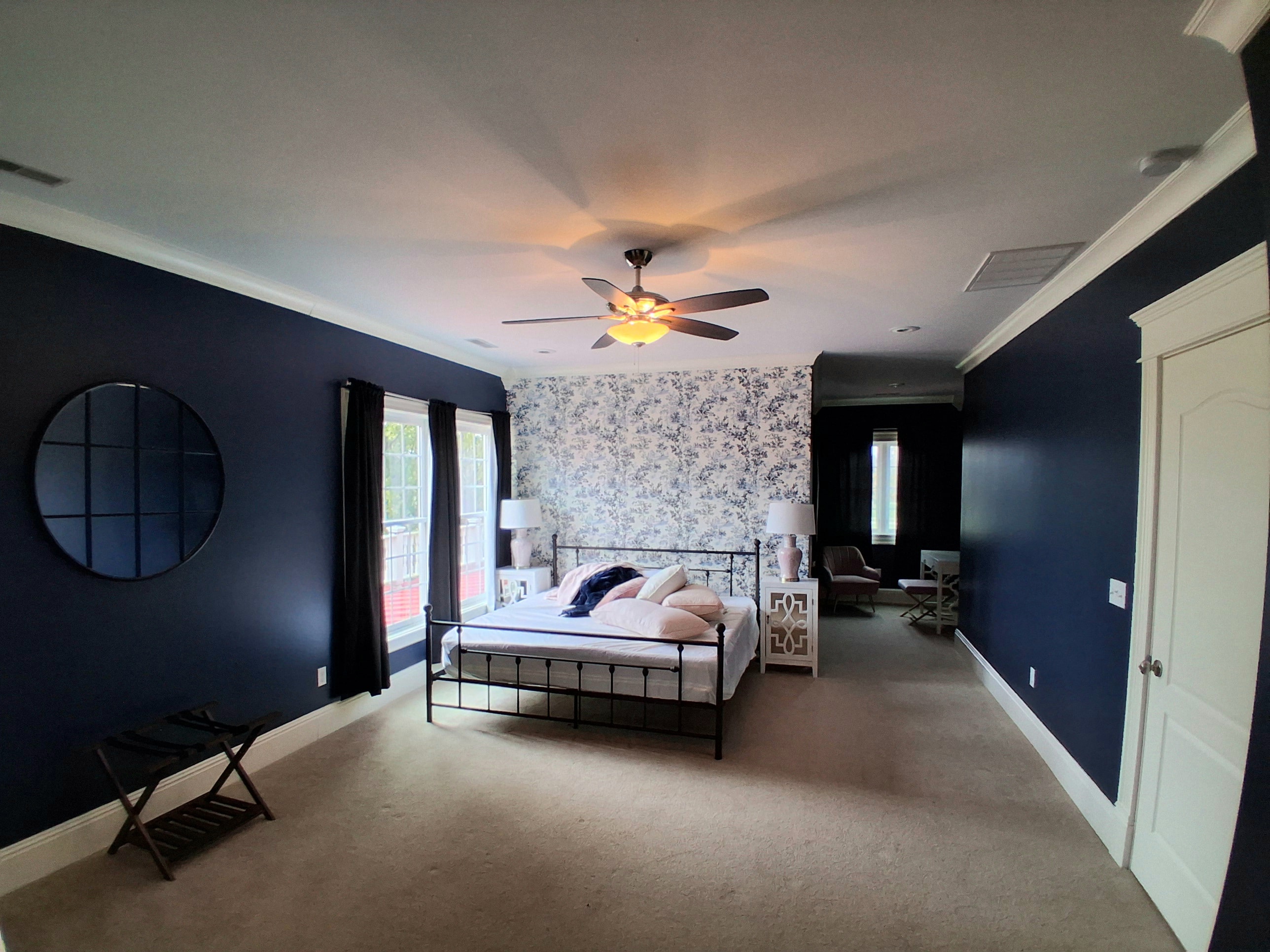 Bedroom with navy blue painted walls and wallpaper accent